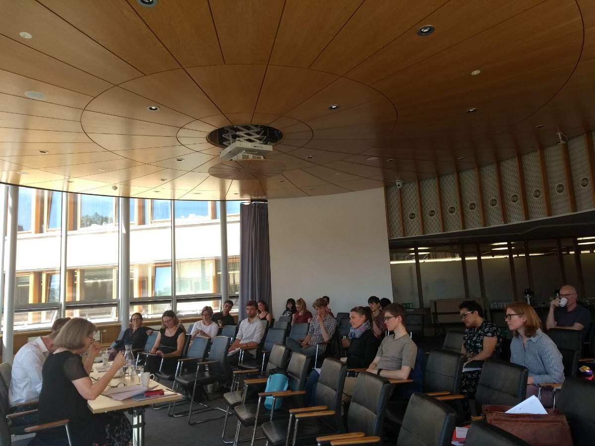 "people sitting at a conference listening to a presenter"